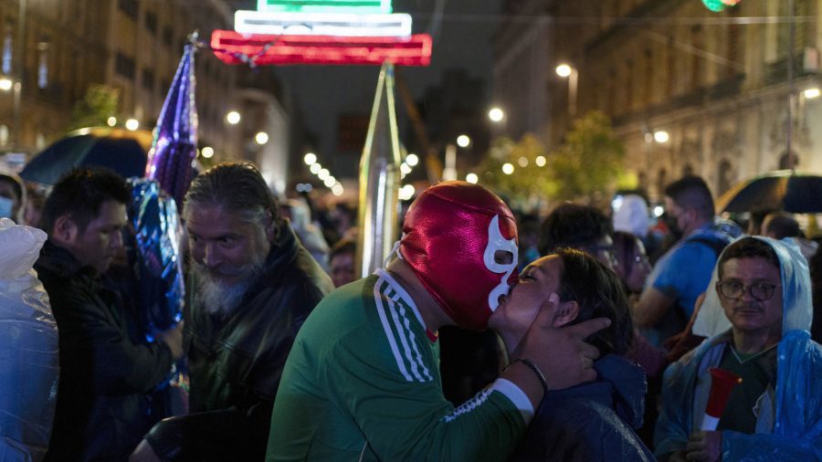 A man wears a Lucha Libre wrestler's mask kisses a woman during the Independence Day celebrations at Mexico City's main square the Zocalo, Thursday, Sept. 15, 2022. (AP Photo/Eduardo Verdugo)